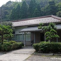 山陰本線・居組駅、古い木造駅舎の前には緑豊かな庭園風の一角